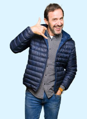 Gülümseyen kış ceket giyen orta yaş yakışıklı adam el ve parmak telefonda konuşmak ile telefon jest yapıyor. Kavramları iletişim.