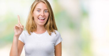 Başarılı fikirle izole arka plan üzerinde işaret parmağı rahat beyaz t-shirt giyen güzel ve genç birbayan. Çıktıktan ve mutlu. Bir numara.
