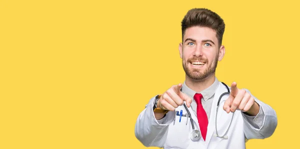 医療を着た若いハンサムな医者の男は 指でカメラにポインティングをコートし 肯定的な陽気な笑顔 — ストック写真