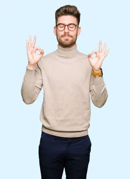 戴眼镜的年轻英俊的商人放松和微笑 闭着眼睛用手指做冥想手势 瑜伽概念 — 图库照片