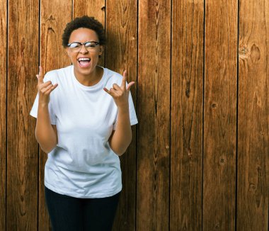 Deli ifade rock simge elle yapıyor ile bağırarak izole arka plan üzerinde gözlük güzel genç Afro-Amerikan kadın. Müzik yıldızı. Ağır kavramı.
