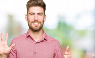 Genç yakışıklı iş rahat adam gösteren ve parmakları ile işaret ederken altı numara kendinden emin ve mutlu gülümseyerek.