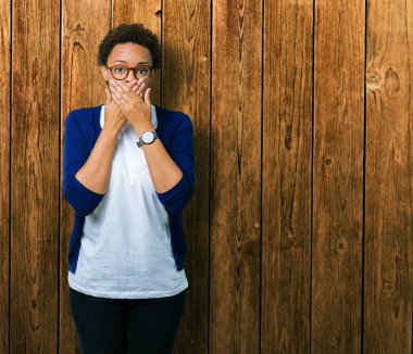 Genç güzel Afrikalı-Amerikalı kadın üzerinde gözlük takan arka plan ağız hata için elleriyle kapsayan şok izole. Gizli kavramı.