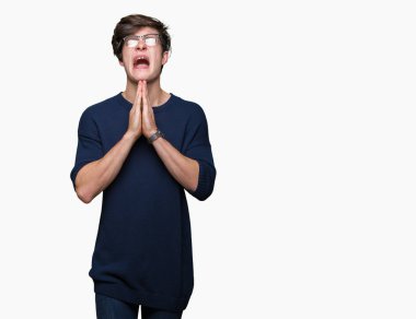 Yalvarıyor ve umut ifade yüzünde çok duygusal ve endişe ile birlikte elleriyle dua izole arka plan üzerinde gözlük takan yakışıklı delikanlı. Bağışlanmak. Din kavramı.