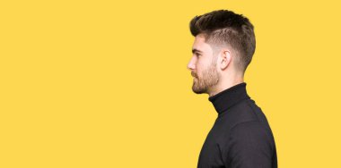 Genç yakışıklı sarışın adam giyen kış kazak tarafına, seyir dinlenmek doğal yüz emin gülümseme ile pozuyla profili.