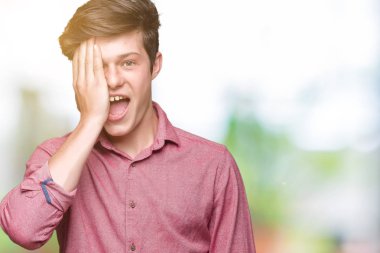 Genç yakışıklı iş adamı el yüz ve sürpriz duygu kendinden emin gülümseme ile tek gözüyle kapsayan izole arka plan üzerinde.