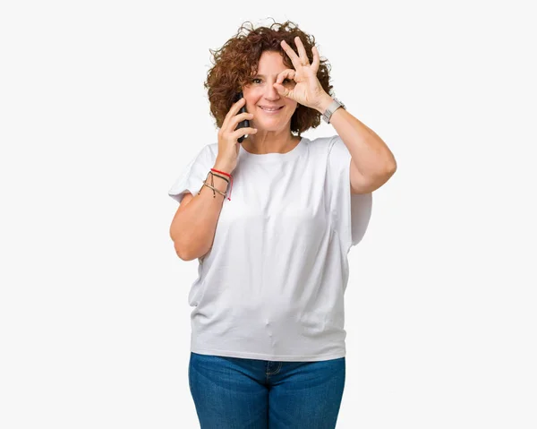 中间一个高级女人在智能手机上谈论孤立的背景与快乐的脸微笑做确定的标志与手在眼睛通过手指看 — 图库照片