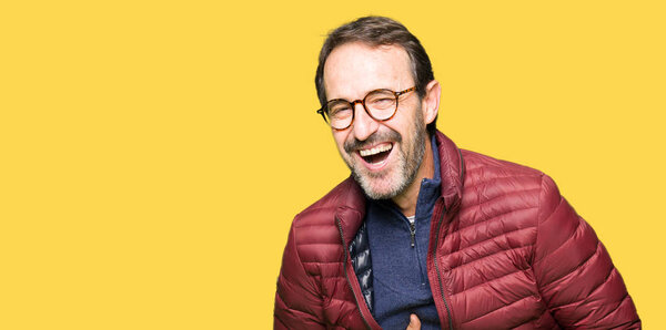 Middle age handsome man wearing glasses and winter coat Smiling and laughing hard out loud because funny crazy joke. Happy expression.
