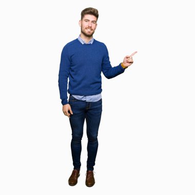 Kameraya bakarak yan el ve parmak ile işaret eden genç yakışıklı bussines adam yüzünde kocaman bir gülümseme ile.