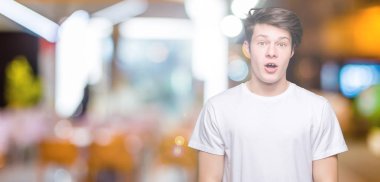 İzole arka plan korkuyor ve şok sürpriz ifade, korku ve heyecan yüz üzerinden Casual beyaz t-shirt giyen genç yakışıklı adam.