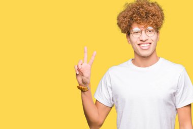 Mutlu yüz zafer işareti yaparken kameraya göz kırpıyor ile gülümseyen gözlüklü afro saçlı Genç yakışıklı adam. İki numaralı.