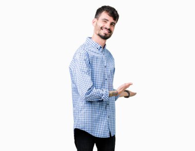 İzole arka plan üzerinde genç yakışıklı iş adamı açık el ile gülümseyen doğal girmek için davet