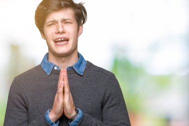 İzole arka plan üzerinde genç yakışıklı zarif adam yalvarıyor ve yüz üzerinde umut ifade ile birlikte eller ile dua çok duygusal ve endişeli. Affedilmesini istiyorum. Din konsepti.