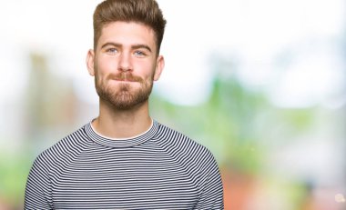 Yakışıklı delikanlı giyen kazak şişirme yanakları komik surat ile çizgili. Ağız ile hava, deli ifade şişirilmiş.