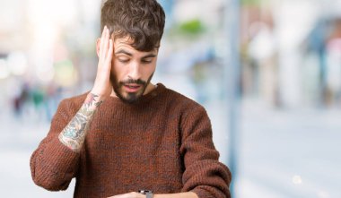 Genç yakışıklı adam giyen kış kazak izole arka plan üzerinde seyretmek zaman endişeli, geç korkuyor arıyorsunuz