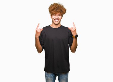 Yakışıklı genç afro saçlı rock simge elle yapıyor deli ifade ile siyah t-shirt bağırarak giyiyor. Müzik yıldızı. Ağır kavramı.