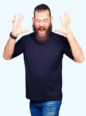 Rahat deli ve silah ile başarı için deli kutluyor t-shirt giyen genç sarışın adam kaldırdı ve heyecanlı çığlık gözler kapalı. Kazanan kavramı