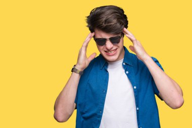 Yakışıklı delikanlı çünkü umutsuz ve stresli baş ağrısı acı izole arka plan üzerinde güneş gözlüğü takıyor ağrı ve migren. Ellerini kafasına.