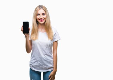 Genç güzel sarışın kadın Smartphone ayakta ve diş gösterilen kendine güvenen bir gülümsemeyle gülümseyerek mutlu bir yüz ile izole arka plan üzerinde gösterilen