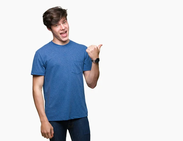 年轻英俊的男人穿着蓝色的 T恤在孤立的背景微笑着 高兴的脸看着 用拇指指着一边 — 图库照片