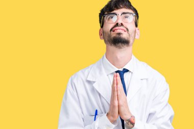 Genç profesyonel bilim adamı adam izole arka plan üzerinde beyaz ceket giyiyor yalvarıyor ve el ile birlikte dua yüz üzerinde umut ifade ile çok duygusal ve endişeli. Affedilmesini istiyorum. Din konsepti.