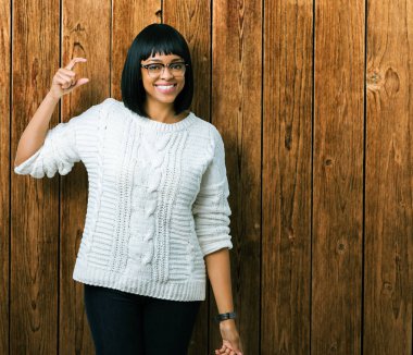 Güzel genç Afro-Amerikan kadın gözlük gülümseyen izole arka plan ve süre seyir ve kamera boyutu işaret parmaklarıyla yapıyor el ile kendinden emin eller üzerinde. Ölçü kavramı.