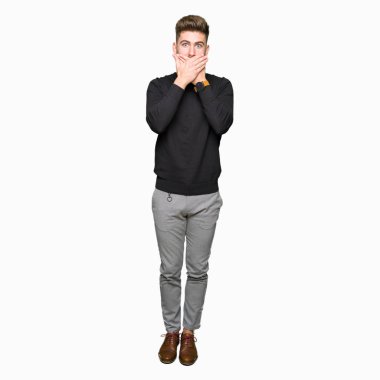 Kış kazak giyen genç yakışıklı sarışın adam yanlışlık için eller ile ağız kapsayan şok. Gizli konsept.