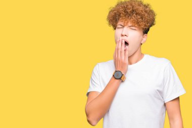 Casual beyaz t-shirt giyen afro saçlı yakışıklı delikanlı ağız el ile kapsayan yorgun esneme sıkılmış. Restless ve uyku hali.