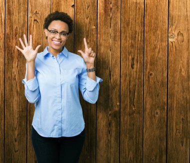 Genç güzel Afro-Amerikan iş kadını gösterilen ve parmakları ile işaret izole arka plan üzerinde kendinden emin ve mutlu gülümseyerek süre yedi numara.