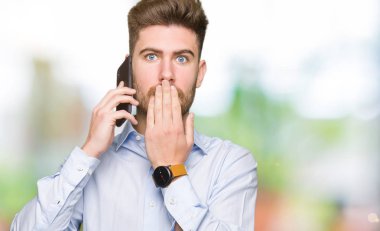 Akıllı telefon kapağı ağız üzerinde konuşan genç yakışıklı adam iş hata için utanç ile şok, korku ifadesi, sessizlik, gizli kavram korkmuş