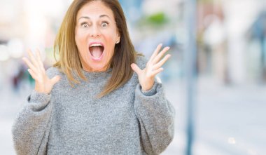 Üzerinde kış kazak giyen güzel orta yaş kadın deli kutluyor arka plan izole ve başarı için kaldırdı kollarını açarak hayrete ve heyecanlı çığlık gözleri açık. Kazanan kavramı