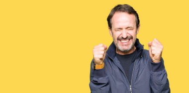 Orta yaş yakışıklı adam bir ceket silah ile başarı için heyecanlı zafer kutluyor gülümseyen kaldırdı. Kazanan kavramı.