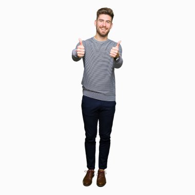 Çizgili süveter onaylama giyen genç yakışıklı adam el ile pozitif jest yapıyor gülümseyen ve başarı için mutlu yaşasın. Kamera, kazanan jest arıyorsunuz.