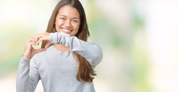 若い美しいブルネット女性のハートマークと手で形を示す愛の笑みを浮かべて孤立の背景の上にセーターを着ています ロマンチックな概念 — ストック写真