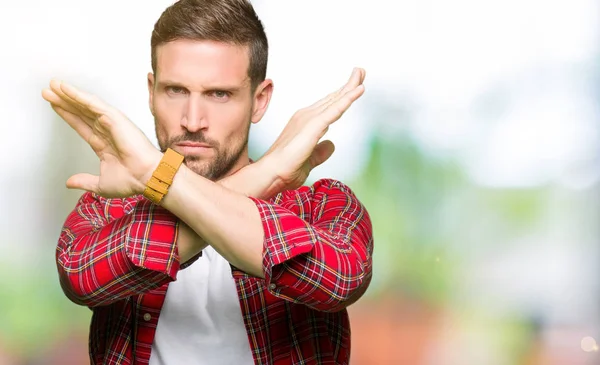 Yakışıklı adam giyiyor rahat gömlek ret ifade geçiş silah eksi işareti, kızgın surat yapıyor