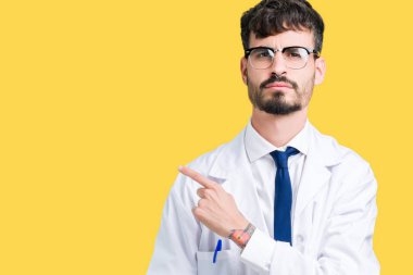 Beyaz önlük üzerinde izole giyen genç profesyonel bilim adam arka plan işaretçi el parmak tarafı gösteren reklam, ciddi ve sakin yüz için