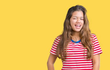 Seksi bir ifadeyle, neşeli ve mutlu yüzünü kameraya bakarak göz kırpıyor izole arka plan üzerinde tişört giyen genç güzel esmer kadın çizgili.