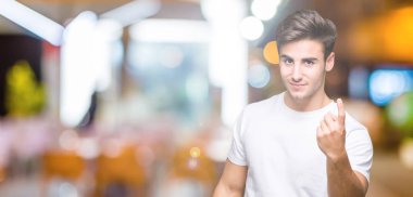 Beckoning gel burada mutlu ve gülümseyerek el davet ile jest izole arka plan üzerinde beyaz t-shirt giyen genç yakışıklı adam