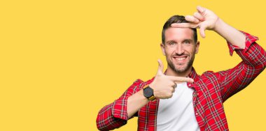 Yakışıklı adam elleriyle yapım çerçeve ve parmakları ile mutlu yüz gülümseyen rahat gömlek giymiş. Yaratıcılık ve Fotoğrafçılık kavramı.