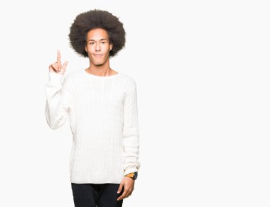 Afro saç içeren genç Afrikalı Amerikalı adam kış kazak gösteren ve parmaklar iki numarası ile işaret kadar güven ve mutlu gülümseyen.