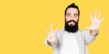 Uzun saç, sakal ve gösterilen ve parmakları ile işaret küpe ile genç adam kendinden emin ve mutlu gülümseyerek süre sekiz numara.