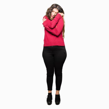 Kendini mutlu ve olumlu sarılma, kendinden emin gülümseyen kırmızı kazak giyen genç güzel kadın. Kendi aşk ve öz bakım