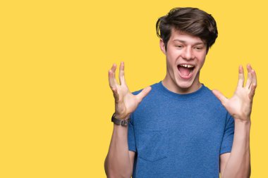 Genç yakışıklı adam izole arka plan üzerinde mavi t-shirt giyen deli kutluyor ve kollarını kaldırdı ve açık gözleri heyecan çığlık ile başarı için hayran. Kazanan kavramı