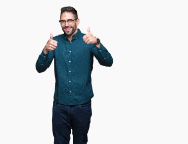 Genç yakışıklı iş adamı izole arka plan başarı işareti el ile pozitif jest yapıyor üzerinde gözlük takan başparmak gülümseyen ve mutlu. Neşeli bir ifadeyle, kazanan jest kameraya bakıyor.