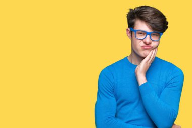 Yakışıklı delikanlı seyir yorgun ve bıkkın ile depresyon sorun Çapraz kollar ile izole arka plan düşünme üzerinde mavi gözlük.