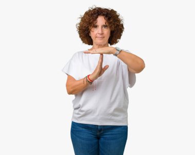 İzole arka plan yapıyor zaman aşımı jest elle, sinirli ve ciddi bir yüz üzerinde beyaz t-shirt giyen güzel orta ager üst düzey kadın