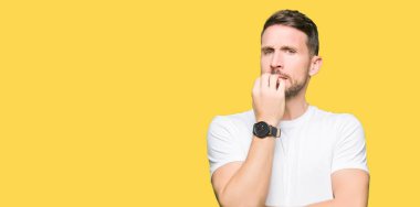 Yakışıklı adam stresli ve gergin ile seyir casual beyaz t-shirt giyen tırnak ısırma dudaklarından eller. Anksiyete sorunu.