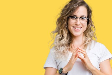 Arka plan eller üzerinde gözlük güzel sarışın genç kadın birlikte izole ve rahat ve neşeli gülümseyen parmak çarpı işareti. Başarı ve iyimser