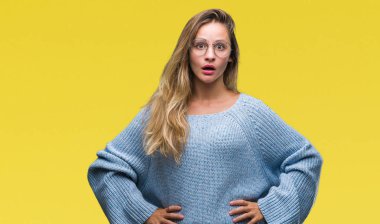 Kazak ve gözlük korkuyor ve şok sürpriz ifade, korku ve heyecan yüz ile izole arka plan üzerinde giyen genç güzel sarışın kadın.