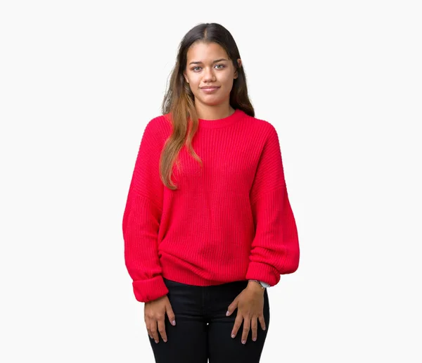 分離背景リラックス顔に真剣な表情で上赤冬のセーターを着た若い美しいブルネット女性 シンプルで自然なカメラを見てください — ストック写真